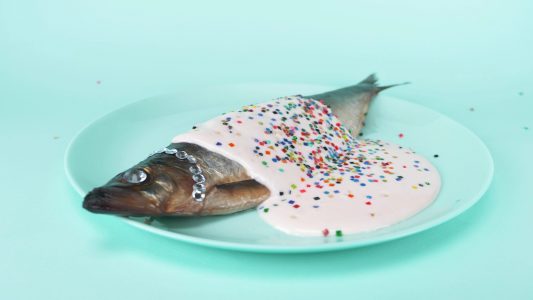 图像：在盘子上的鱼，覆盖在白色酱汁上面用五彩纸屑
