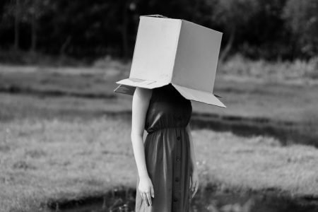 图片：女人站在田野里，头顶上有一个大盒子。
