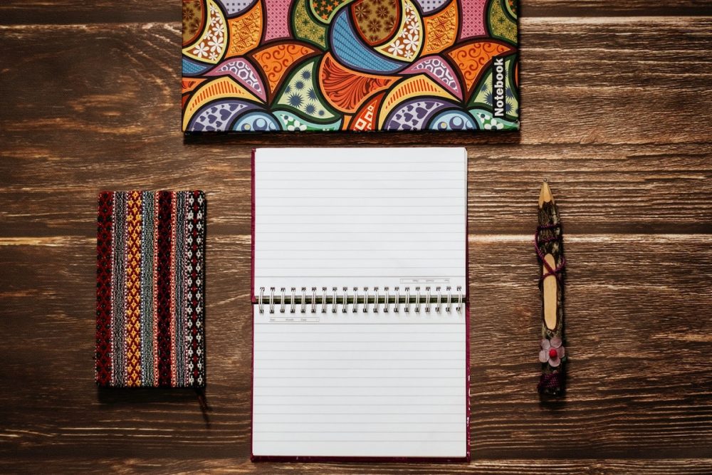 图片：一本五颜六色的笔记本，铅笔盒，铅笔和开放日计划者在一张木桌上。