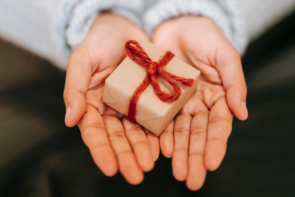 图片：一个女人的张开手拿着一个小的包裹的礼物。