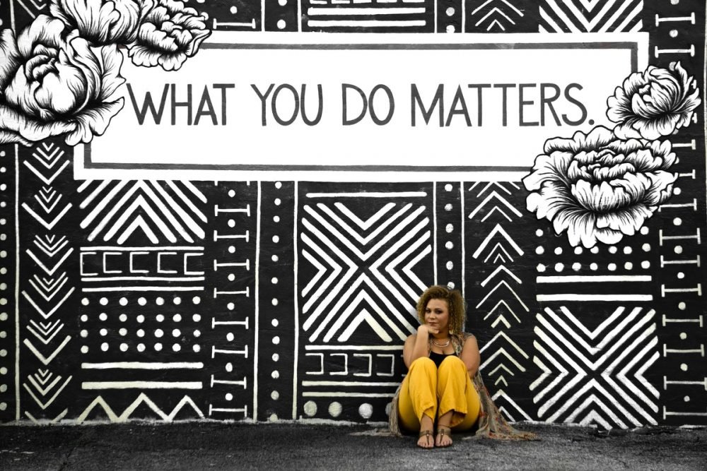 图像：一个女人坐在墙上，上面涂有黑白壁画，“您所做的事情都很重要”。