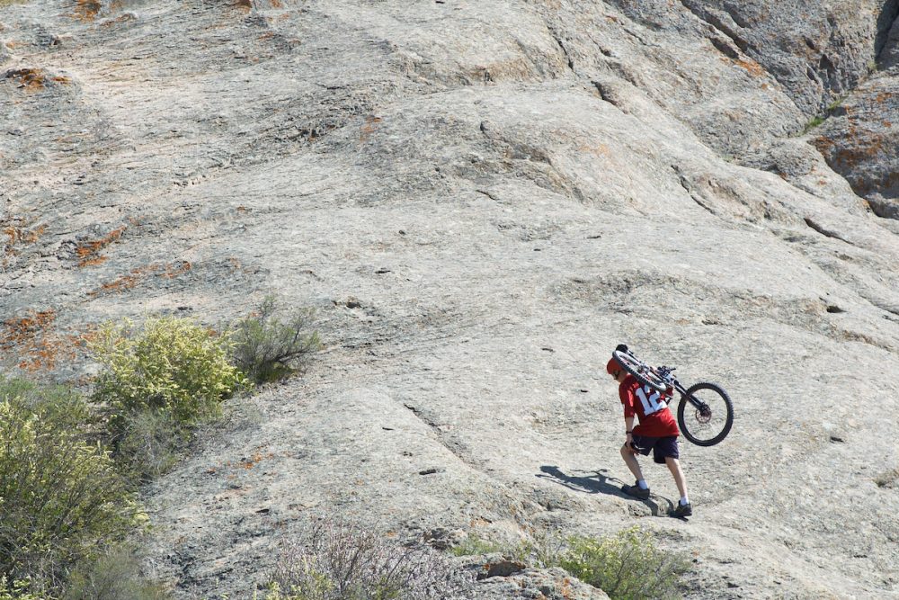 图片：一辆山地车手步行爬山，背上骑自行车。