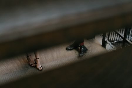 图像：通过楼梯之间的缝隙，只有一个女人的脚和火车平台上的男人的脚就可以看到。