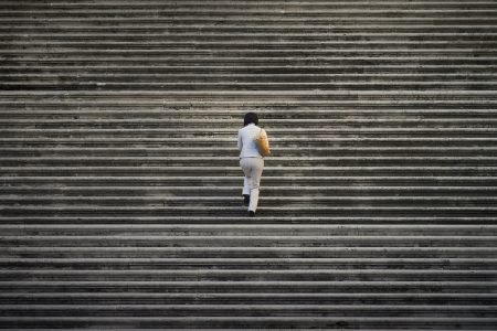 图片:一个孤独的女人走上一组巨大的楼梯，楼梯从画框的四周延伸出去。