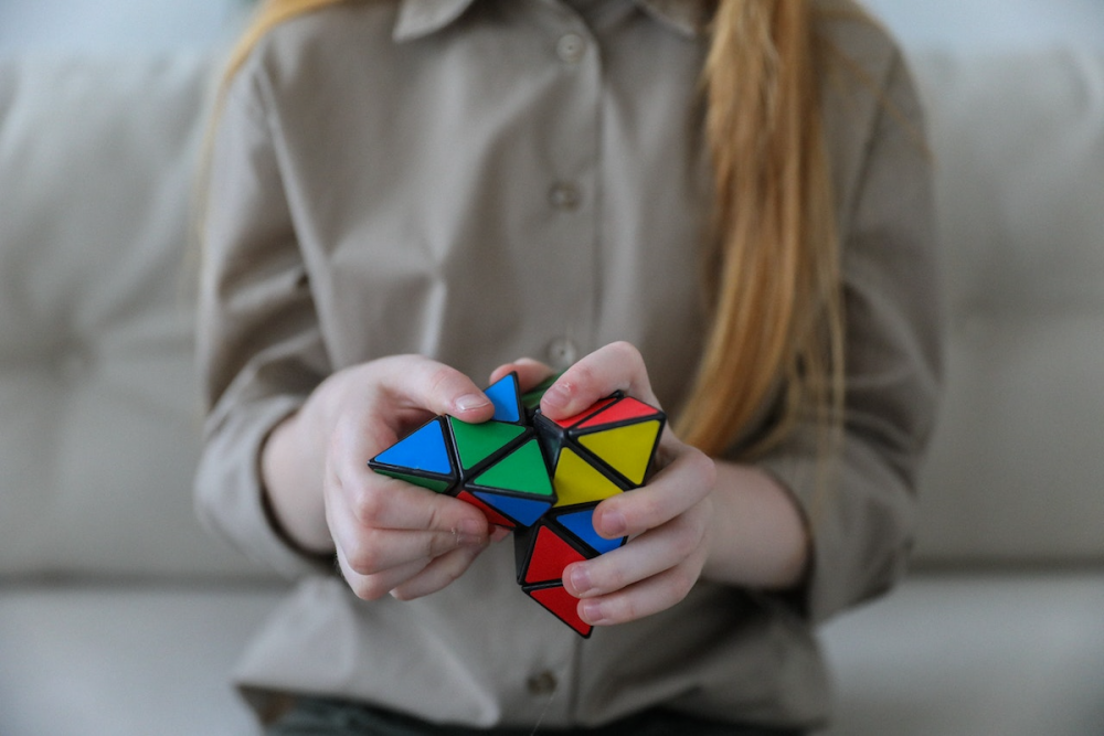 图片:一名年轻女子的双手正在解金字塔，一种金字塔形状的魔方式谜题。