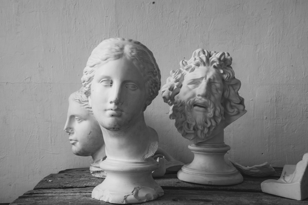 图片:三个古色古香的雕塑头像放在一张粗糙的木桌上。