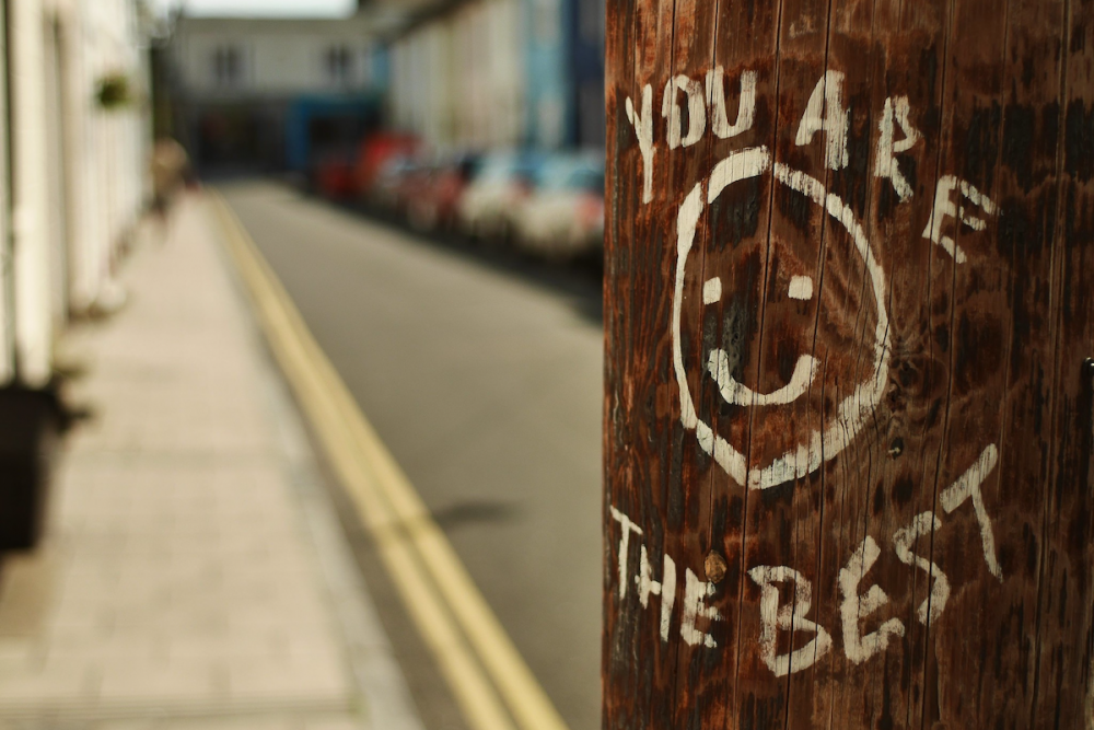 图片:一根城市电线杆，上面有人画了一个笑脸和“你是最好的”的字样。