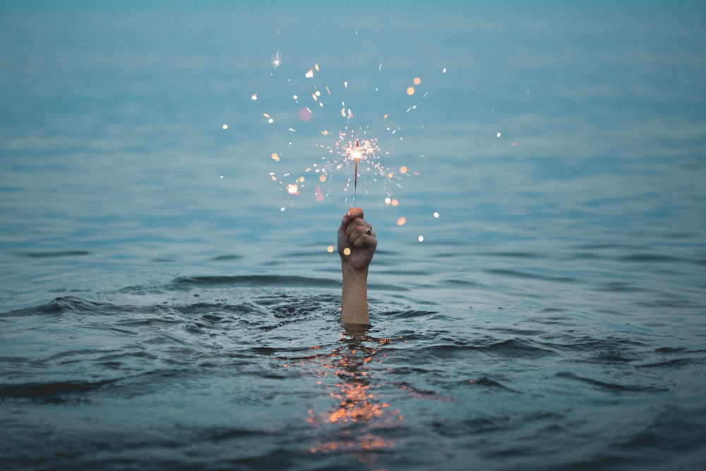 从水下伸出一只手，手里拿着一个火花。