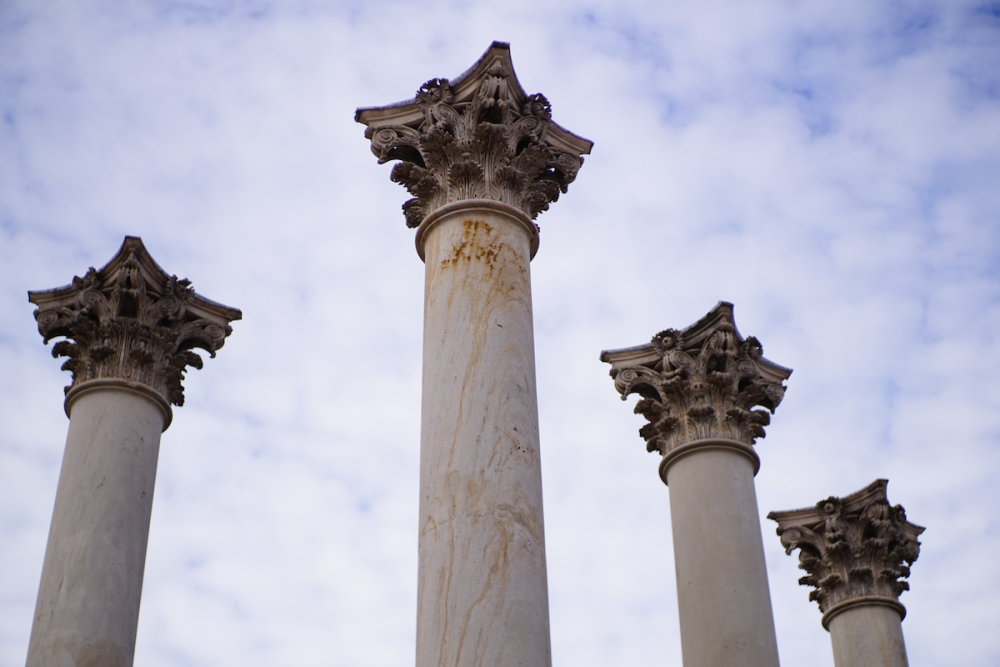 图片:四根白色的科林斯柱矗立在多云的蓝天下。